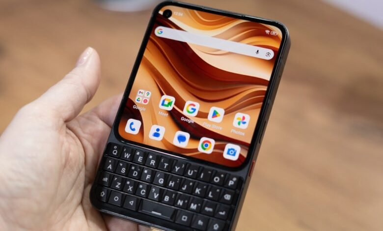 Hand holding a smartphone with a physical QWERTY keyboard.