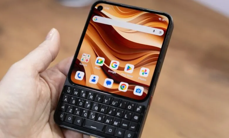 Hand holding a smartphone with a physical QWERTY keyboard.