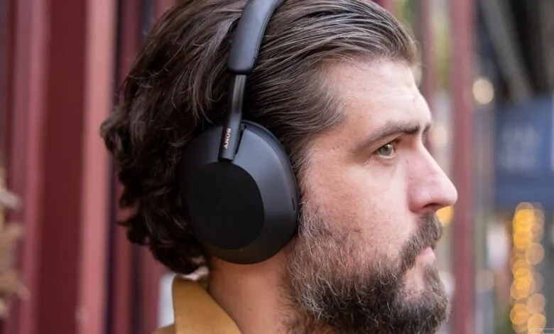 Man wearing black Sony noise-canceling headphones in an outdoor setting.