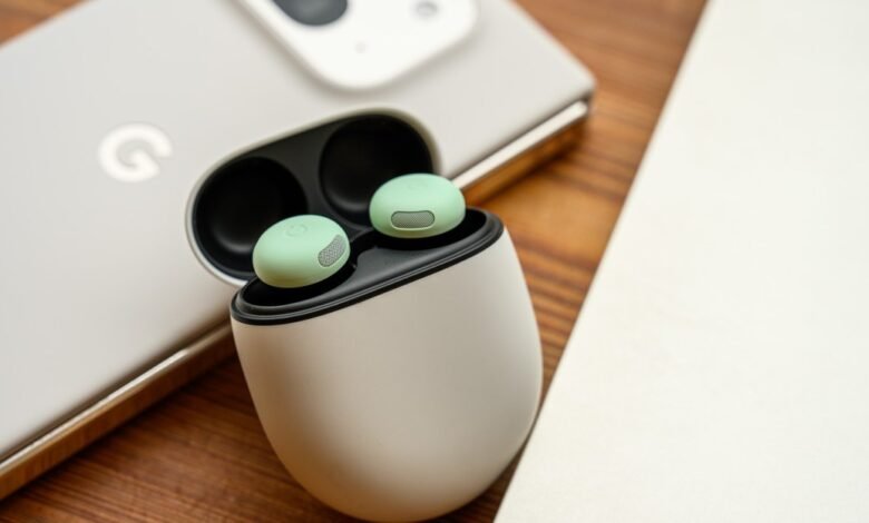 Mint green Google Pixel Buds Pro in charging case next to a Pixel phone.
