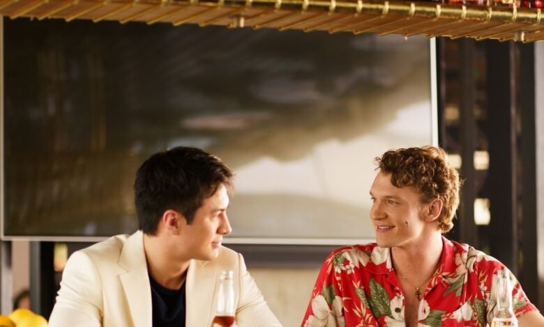 Connor Storrie and Hudson Williams at a bar, smiling.