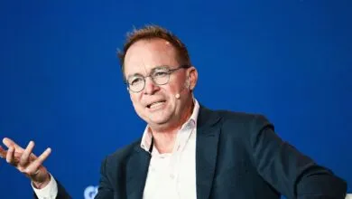 Mick Mulvaney speaking at an event with a blue background.