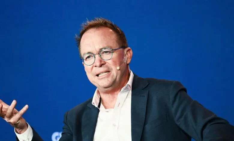Mick Mulvaney speaking at an event with a blue background.