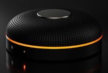 Black round speaker with orange accent light on dark surface.