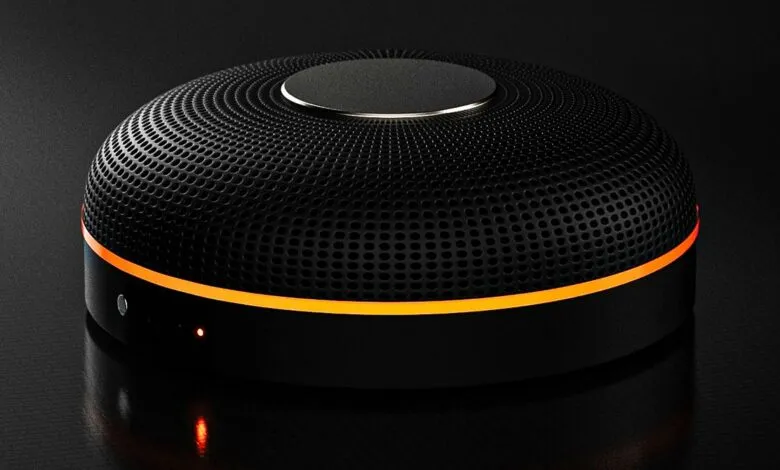 Black round speaker with orange accent light on dark surface.
