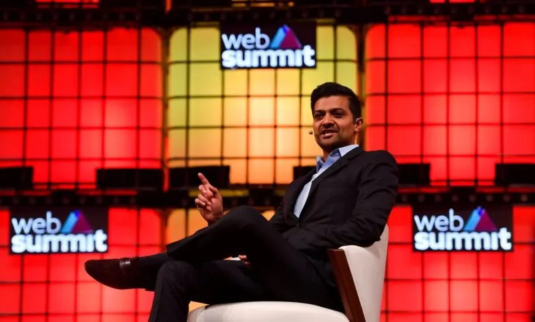 Man in suit sits in chair on stage at Web Summit conference.