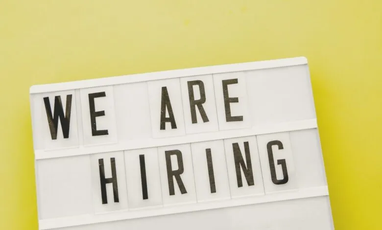 White lightbox sign displaying 'We Are Hiring' on yellow background.