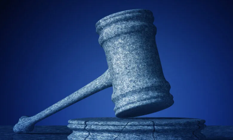 Stone gavel resting on a cracked base against a dark blue background.