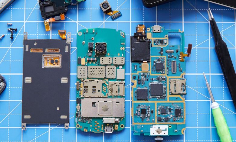 Disassembled smartphone components and tools on a blue grid surface.