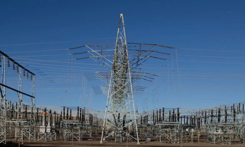 Electrical substation with towers and power lines against a clear blue sky.