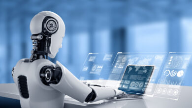 White humanoid robot using laptop with data visualizations on screen.