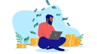 Person using laptop with money falling, stacks of coins around them.