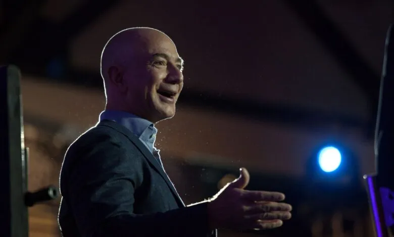 Jeff Bezos smiles and gestures during a speech on stage.
