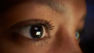 Close-up of a brown eye reflecting a bright screen.