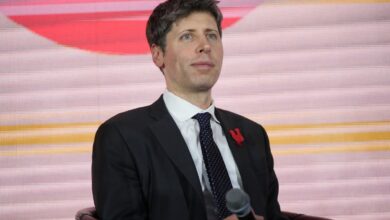 Man in suit holding microphone, looking upwards slightly.