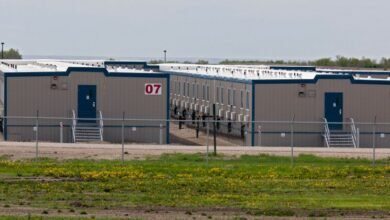 Modular housing units with numbered entrances behind a chain-link fence.