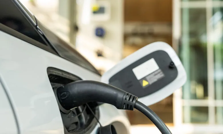 Electric car charging: black cable plugged into white vehicle.