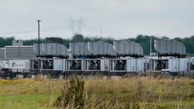 Rows of modular data center units with cooling systems, cloudy sky.