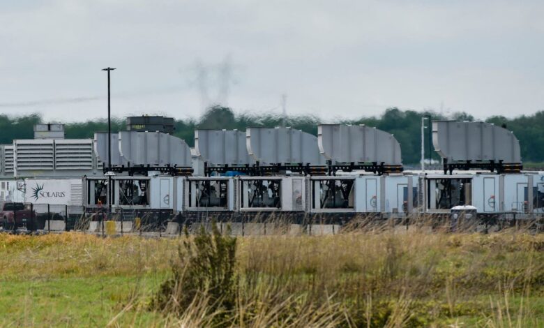 Rows of modular data center units with cooling systems, cloudy sky.