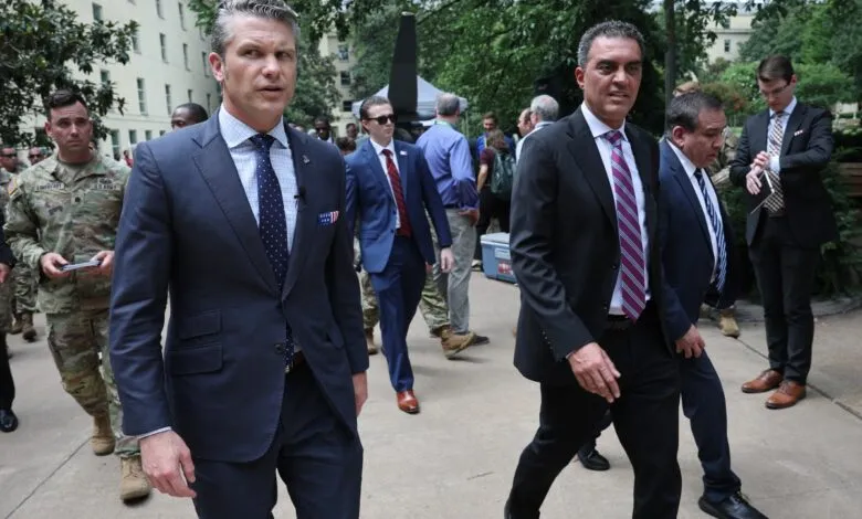 Pete Buttigieg walks with officials in suits and military uniforms.