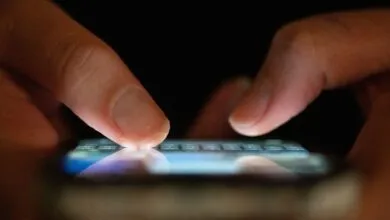 Close-up of fingers typing on a glowing smartphone screen.