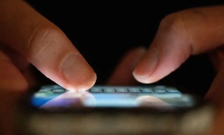 Close-up of fingers typing on a glowing smartphone screen.