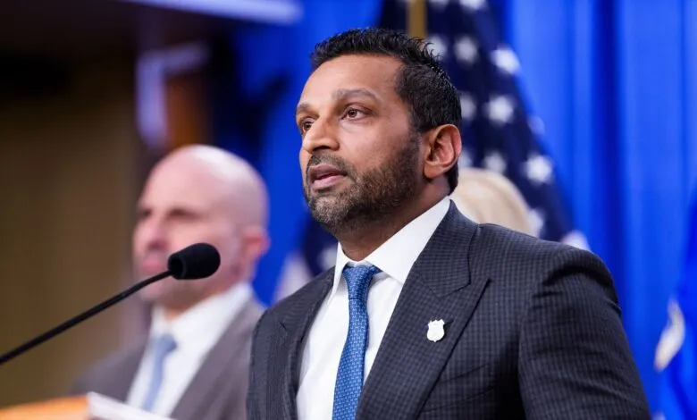 Man in suit speaks at podium with American flags in background.