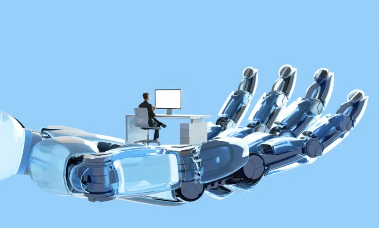 Robot hand gently supports a man working at his desk, symbolizing AI's role in the future of work.