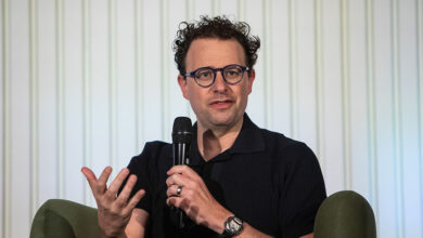 Dario Amodei speaking into a microphone, gesturing with his hand.
