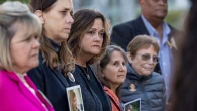 Mournful group of people holding photos at an outdoor memorial.