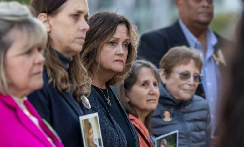 Mournful group of people holding photos at an outdoor memorial.