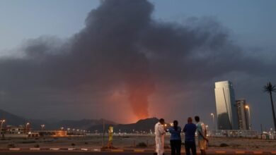 People watch a large plume of smoke rising from an explosion in Fujairah.