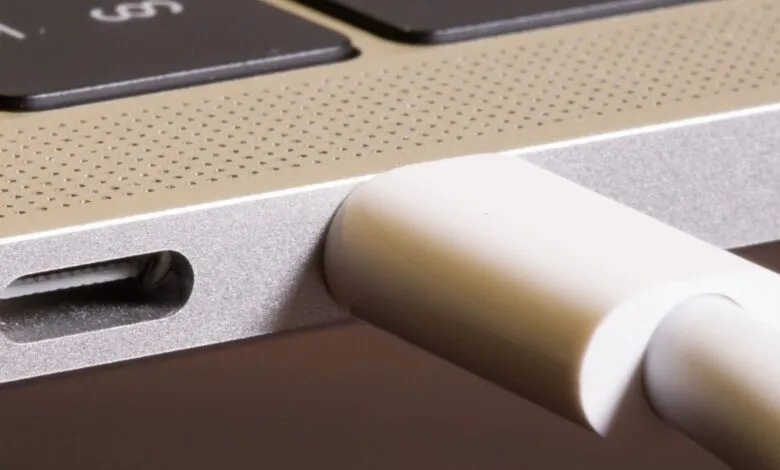 Close-up of a white USB-C cable plugged into a silver laptop.