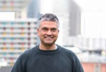 Zain Asgar, Gimlet Labs CEO, smiles in front of city buildings.