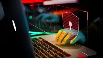 Hands type on laptop with digital shield overlay, cybersecurity concept.