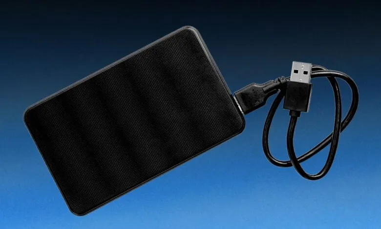External hard drive with USB cable on blue gradient background.