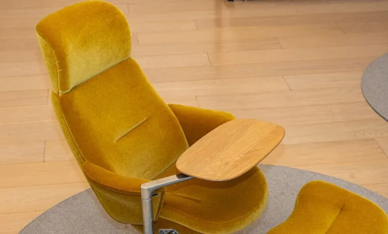 Yellow lounge chair with wooden side table and footrest.