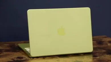 Lime green Apple MacBook laptop on a wooden surface, against a dark blue background.