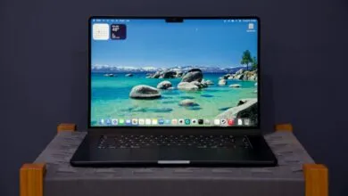 Black laptop displays a scenic lake view with mountains in the background.