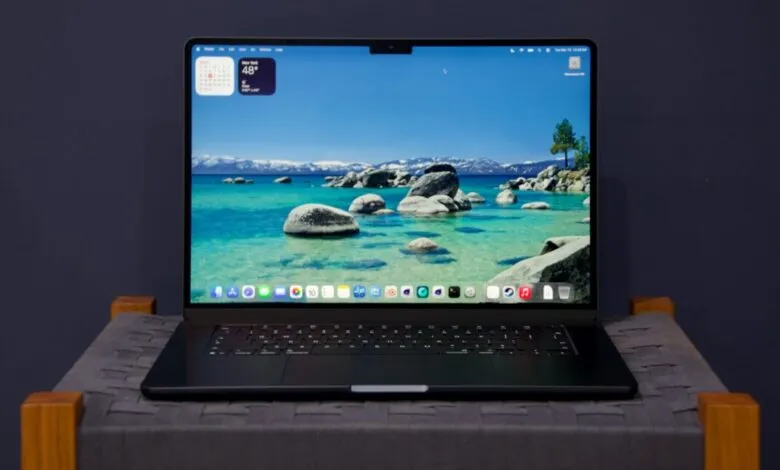 Black laptop displays a scenic lake view with mountains in the background.