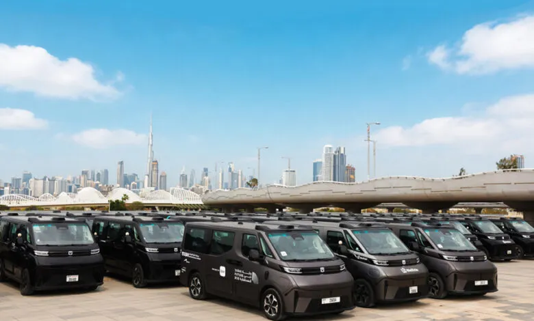 Fleet of autonomous vehicles parked with Dubai skyline in background.