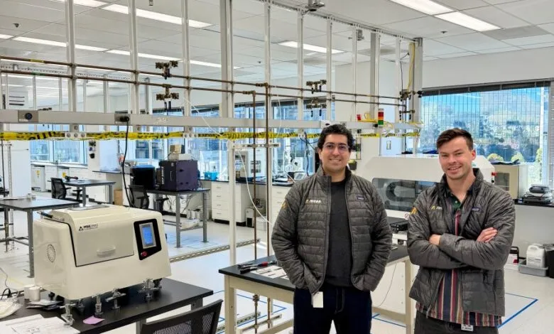 Two men stand in a modern, well-lit laboratory with scientific equipment.
