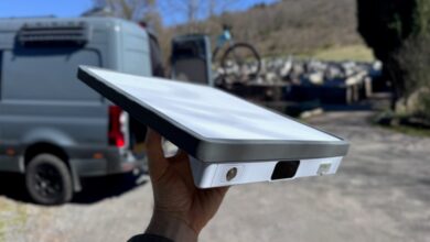 Hand holding a Starlink dish with a van and bike in the background.