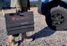 Person carries Bluetti solar panel near van with off-road tires.