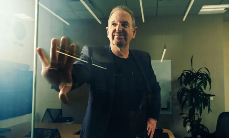 Man in suit presses hand against glass wall in modern office space.