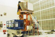 Technicians work on the Swift spacecraft in a clean room environment.