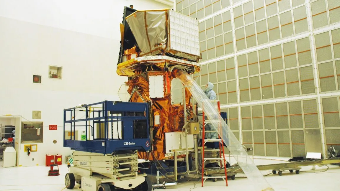 Technicians work on the Swift spacecraft in a clean room environment.