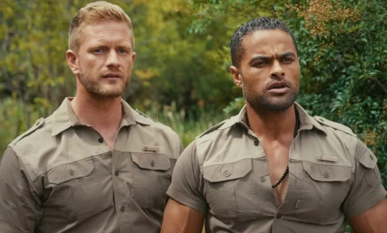 Two men in khaki shirts stand outdoors, looking alert.