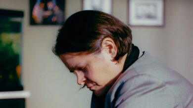 Woman in gray jacket looking down in an office setting.