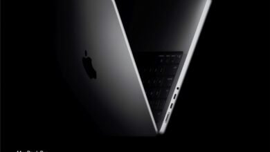 Sleek, partially open MacBook Pro with Apple logo against a dark background.